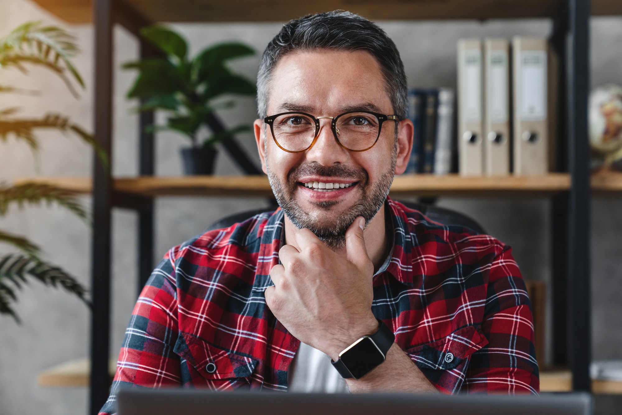 Head shot portrait of positive freelance businessman in eyeglasses sitting at home office